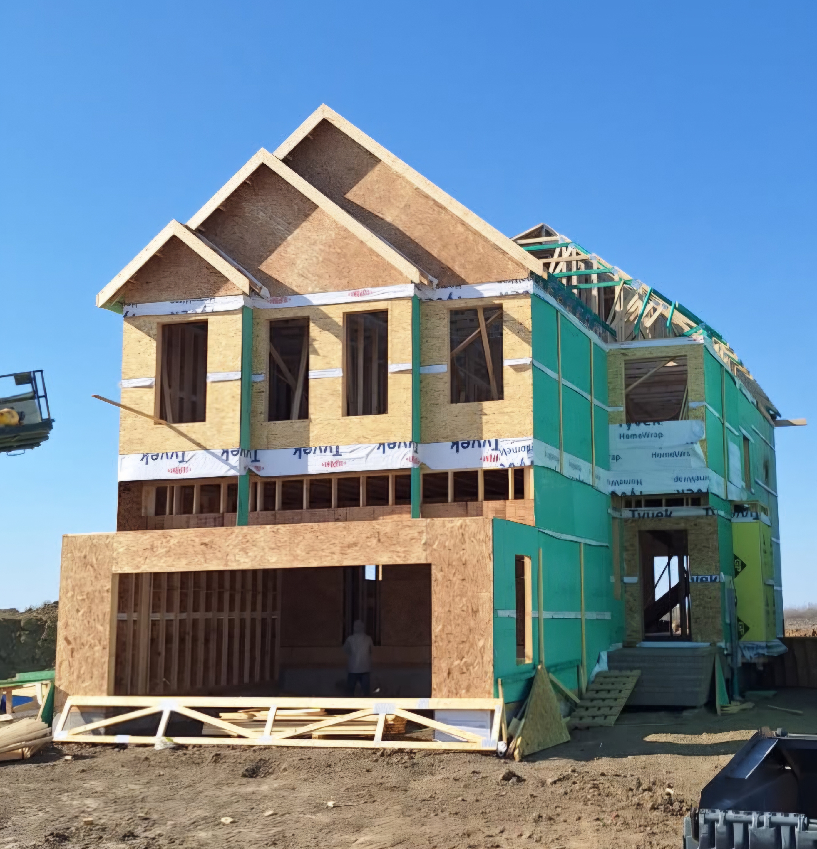 Three-storey wood-frame house under construction with sheathing and house wrap